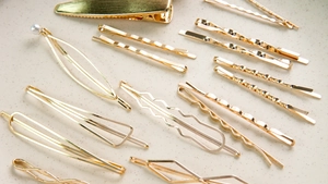 Macro shot of elegant gold hair clips set including pearl details and geometric metal designs