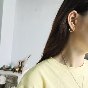 Close-up of a model wearing irregular gold hoop earrings in minimalist silver style