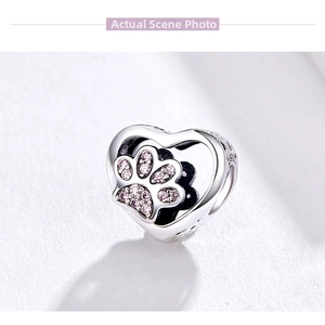 Macro shot of S925 sterling silver heart charm with pink gemstone pet paw print