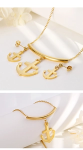 Close-up of golden anchor jewelry set with polished necklace and matching stud earrings