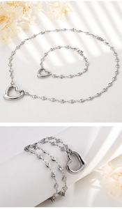 Detailed view of silver heart-shaped necklace and bracelet set with delicate openwork charms