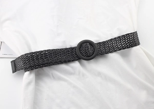 Vue détaillée d'une ceinture tressée noire avec boucle ronde sur un chemisier blanc