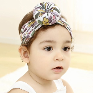 Primer plano de un bebé con diadema de nailon con estampado floral y nudo suave