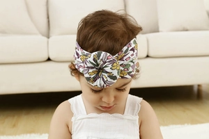 Primer plano de una niña con diadema de nailon suave con estampado floral bohemio.