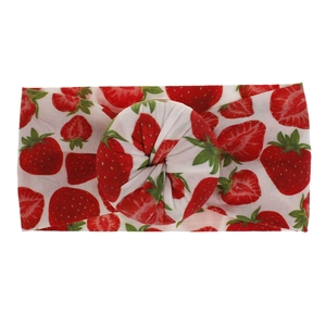 Detalle de diadema para bebé en nailon blanco con estampado de fresas rojas y nudo central