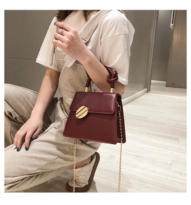 Close-up of wine red crossbody bag with knotted handle and golden chain strap