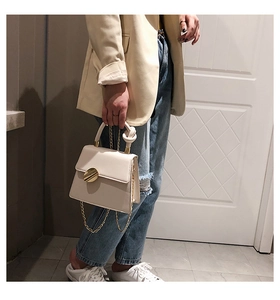 White PU leather handbag with gold metal clasp and knotted handle detail worn by model
