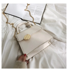 Chic cream white crossbody bag with gold hardware and chain strap on soft white fabric