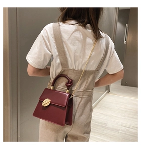 Burgundy PU leather crossbody bag with knot handle and golden metal lock shown on shoulder