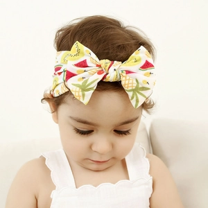 Close-up of a cute baby girl wearing a soft nylon headband with colorful fruit print bow