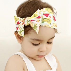 Close-up of a soft nylon baby headband featuring a vibrant fruit print and bow detail