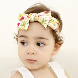 Close-up of a baby wearing a fruit print nylon headband with a large decorative bow