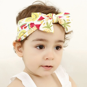 Close-up of baby girl wearing a nylon headband with colorful fruit prints and bow