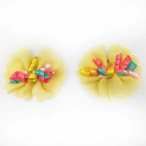 Detail of yellow lace pet hair bows with colorful curly ribbons on a white background