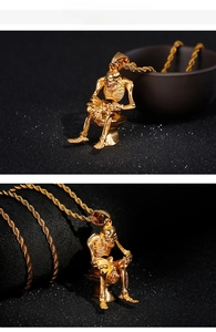 Close-up of unique gold skull pendant sitting on a toilet with a twisted chain