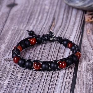 Close-up of lava rock and tiger eye stone beads on a black leather braided bracelet