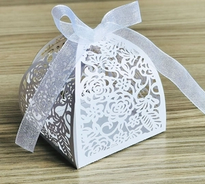 Close-up of laser-cut rose hollow patterns on a white triangular paper wedding favor box