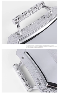Macro detail of silver serving tray with ornate floral relief handles and mirror finish