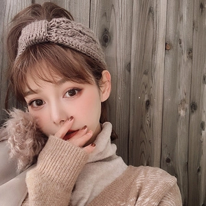 Detailed knit texture of light brown wide bow headband in thick cable-stitch pattern