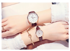 Close-up of couple watches with rose gold cases, white dials and brown leather straps