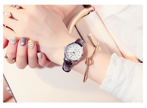 Close-up of a women's silver quartz watch with a white dial and black leather strap