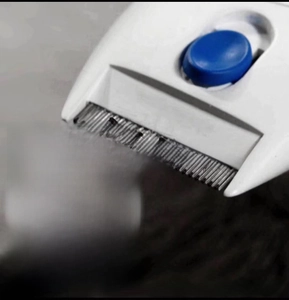 Detail of electric pet flea comb showing fine metal teeth and power button for dog grooming