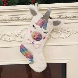Plush unicorn Christmas stocking with sequins hanging on a white decorative fireplace