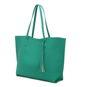 Detail shot of the teal lychee grain tote bag showing metallic buckle and tassel charm