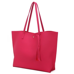Detail of rose pink litchi grain tote bag featuring tassel charm and magnetic buckle
