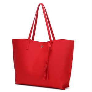 Detailed close-up of red pebbled leather tote with a metal buckle and tassel charm