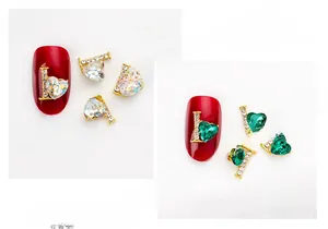 Detailed view of alloy heart and L-letter nail charm with crystals on red nails