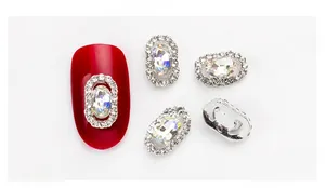 Close-up of oval crystal nail charm with AB rhinestones on a red manicure base