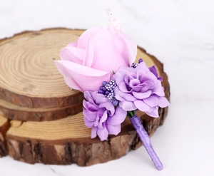 Detailed view of handmade purple and pink rose boutonniere on a rustic wooden log