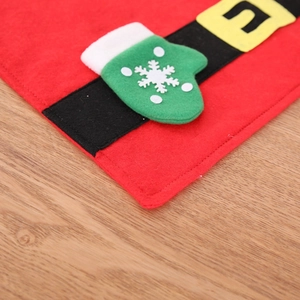 Festive red Christmas table mat with green glove patch and snowflake patterns on wood