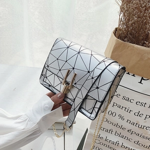Silver geometric patchwork mini crossbody bag with triangular textured flap held by hand