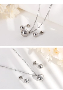 Close-up of silver spherical pendant necklace and stud earrings set with O-chain
