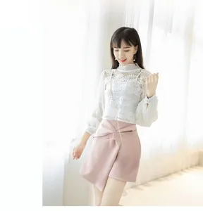 Close-up of white floral lace top and pink asymmetrical mini skirt with evening clutch