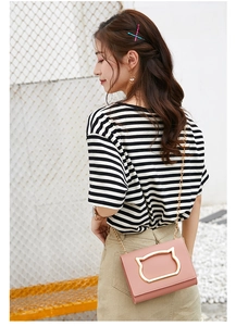 Detailed view of pink leather crossbody bag featuring gold cat buckle and chain strap