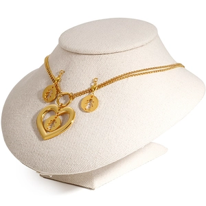 Golden heart necklace and earrings set with child silhouettes on a beige jewelry bust