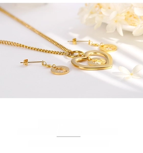 Close-up of gold hollow heart jewelry set with girl silhouette pendant and earrings