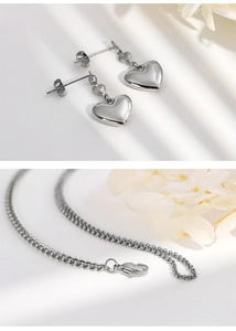 Elegant silver heart necklace and earrings set displayed with white floral accents
