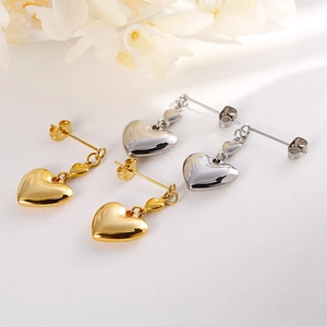 Elegant gold and silver hollow heart-shaped dangle earrings displayed with dried flowers