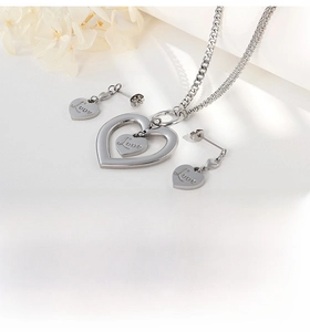 Detailed close-up of silver hollow double-heart necklace and earrings with Love engraving