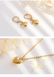 Vue détaillée d'une parure de bijoux cœur en acier doré avec collier et boucles d'oreilles