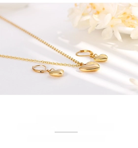 Parure de bijoux cœur dorés polis avec collier et créoles sur un fond propre et sobre