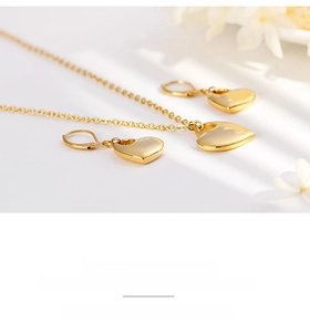 Dettaglio del set di gioielli a cuore in oro lucido con collana e orecchini su fondo bianco