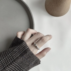 Detail of twisted 925 sterling silver woven ring worn on finger with tweed outfit