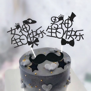 Detail shot of black paper cake toppers with crown and hat designs on a cake