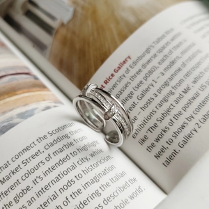 Macro detail of layered 925 silver ring with pavé zirconia on an artistic magazine base