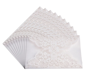 Detailed macro view of laser-cut lace patterns on white paper wedding invitations